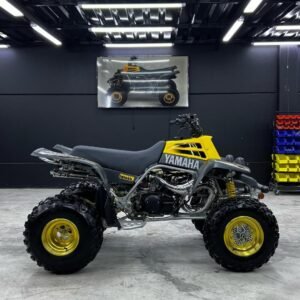 The Yamaha Banshee 350 is powered by a 347cc liquid-cooled, twin-cylinder two-stroke engine derived from Yamaha’s RZ350 motorcycle platform. This setup gives it an extremely aggressive powerband, meaning it accelerates hard and fast when it hits higher RPMs. Stock, it produces around 35–40 horsepower, but modified builds can go much higher. ⚙️ Key Features Engine: 347cc twin-cylinder 2-stroke Transmission: 6-speed manual with clutch Drive: Chain-driven rear wheel (2WD) Starting: Kick start Weight: ~175 kg (386 lbs dry) � Wikipedia Fuel system: Dual carburetors Suspension: Long-travel sport suspension (front & rear discs) 🚀 Performance Top speed (stock): around 70–75 mph (113–121 km/h) � CarInterior Modified: can exceed 85–100+ mph depending on setup Known for extremely fast acceleration and wheel-lifting power