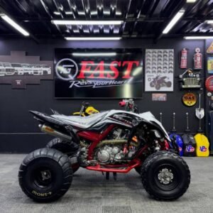 White And Black Yamaha Raptor 700 sport ATV, high-performance quad bike with off-road tires, clean condition, displayed in showroom.